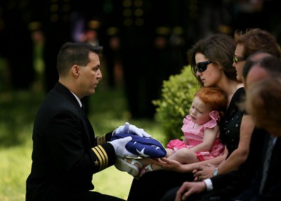 Commander Dave Mundy presents Katrina Zilberman with an American flag during a memorial service on April 8, 2010 for her husband Lt. Miroslav Steven Zilberman, who crashed into the Arabian Sea last week. She is holding their daughter Sarah. (Vicki Cronis-Nohe | The Virginian-Pilot)