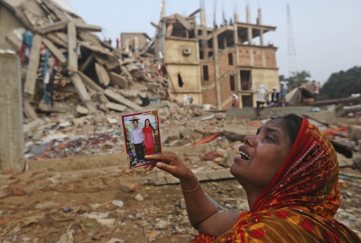 APTOPIX Bangladesh Building Collapse A Bangladeshi woman weeps as she holds a picture of her and her missing husband as she waits at the site of a building that collapsed Wednesday in Savar, near Dhaka, Bangladesh, Friday, April 26, 2013. The death toll reached hundreds of people as rescuers continued to search for injured and missing, after a huge section of an eight-story building that housed several garment factories splintered into a pile of concrete.(AP Photo/Kevin Frayer)