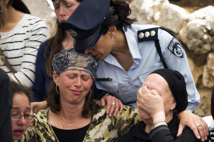 An Israeli policewoman kisses Hadas Mizrahi (C), the widow of Baruch Mizrahi, a senior police officer of the Israel Police intelligence, during the funeral at the military cemetery of Mount Herzl in Jerusalem, Israel, 16 April 2014. Baruch Mizrahi was killed by Palestinian militants on 14 April near the West Bank city of Hebron while driving with his wife and young son who was also injured in the attack, as they where on their way for the Passover dinner. EPA/ABIR SULTAN
