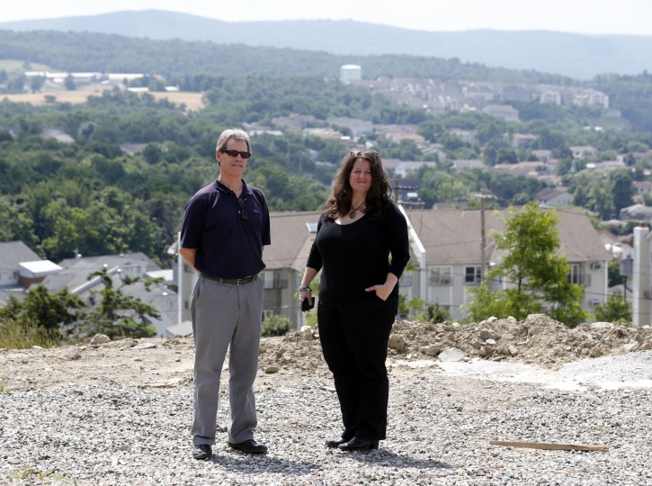 Michael Egan, left, and Emily Convers of United Monroe pose on Tuesday, July 1, 2014, in Kiryas Joel, N.Y. A proposal to grow the village by annexing 164 acres of adjacent land has heated up longstanding tensions involving the insular, traditional community. (AP Photo/Mike Groll)