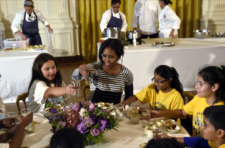 First lady Michelle Obama offers a toast as she sits with school children as they eat lunch in the East Room of the White House following the annual fall harvest of the White House Kitchen Garden in Washington, Tuesday, Oct. 14, 2014.  AP