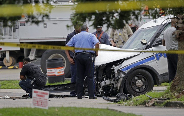 Investigators look over a New Orleans Police department vehicle in which one officer was shot and killed while transporting a prisoner in New Orleans, Saturday, June 20, 2015. The New Orleans Police Department said Officer Daryle Holloway was shot while transporting Travis Boys, who managed to get his handcuffed hands from behind his back to the front, grab a firearm and shoot the officer. A manhunt was underway for the 33-year-old Boys, according to Police Chief Michael Harrison. (AP Photo/Gerald Herbert)