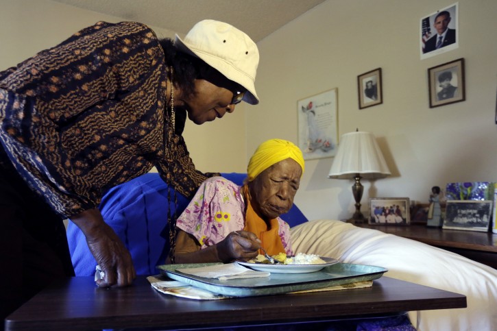In this Monday, June 22, 2015 photo, Lois Judge, left, helps her aunt Susannah Mushatt Jones, 115, during breakfast in Jones' room at the Vandalia Avenue Houses, in the Brooklyn borough of New York. Jones and Emma Morano, of Verbania, Italy, who is also 115, are believed to be the last two people in the world with birthdates in the 1800s. (AP Photo/Richard Drew)
