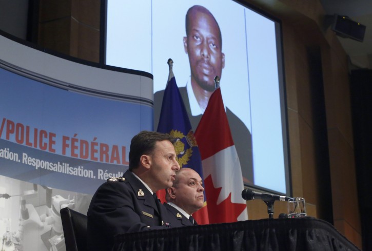 Royal Canadian Mounted Police assistant commissioner James Malizia, left, and Inspector Paul Mellon speak at a press conference at RCMP headquarters in Ottawa, Ontario, about the arrest of a Somali man Ali Omar Ader, shown on the screen, for his involvement in the kidnapping of Canadian journalist Amanda Lindhout and Australian photojournalist Nigel Brennan, Friday, June 12, 2015. (Patrick Doyle/The Canadian Press via AP)