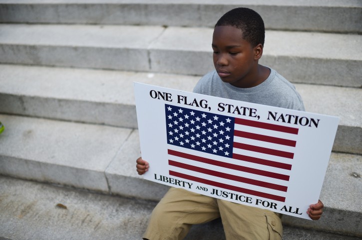 Lennos Lemon, 12, sits on the South Carolina Statehouse steps during a rally to take down the Confederate flag, Saturday, June 20, 2015, in Columbia, S.C. Rep. Doug Brannon, R-Landrum, said it's past time for the Confederate flag to be removed from South Carolina's Statehouse grounds after nine people were killed at the Emanuel A.M.E. Church shooting. (AP Photo/Rainier Ehrhardt)