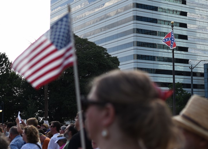 Salley Rickenbacker, of Columbia, S.C., holds an U.S flag as the Confederate flag flies nearby during a rally to take down the flag at the South Carolina Statehouse, Saturday, June 20, 2015, in Columbia, S.C. Rep. Doug Brannon, R-Landrum, said it's past time for the Confederate flag to be removed from South Carolina's Statehouse grounds after nine people were killed at the Emanuel AME Church shooting. (AP Photo/Rainier Ehrhardt)