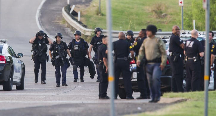 Dallas SWAT  and other police officers gather at the intersection of Interstate 45 and E Palestine Street, where police have cornered a suspect in a van on Saturday, June 13, 2015 in Hutchins, Texas.   Police Chief David Brown says a police sniper has shot the suspect in an overnight attack on police headquarters and that the department is checking to see if he's still alive. Brown says investigators believe the man acted alone in the early-morning attack on Dallas police headquarters, despite early witness reports that others may have taken part.    (Ashley Landis/The Dallas Morning News via AP
