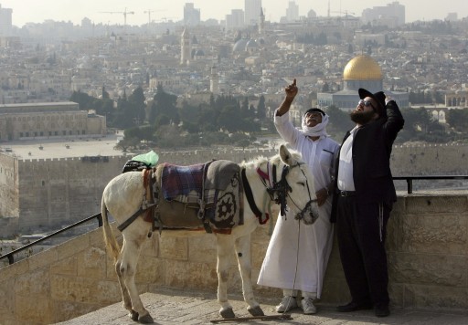 FILE - In this Feb. 22, 2007 file photo, a Palestinian who offers donkey rides to tourists shares a laugh with an Ultra-orthodox Jewish man at the Mount of Olives, overlooking Jerusalem's Old City. (AP Photo/Oded Balilty, File)