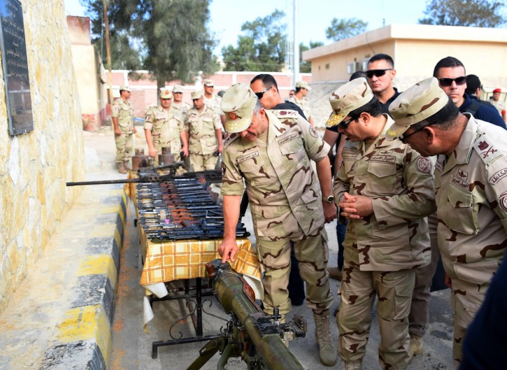 In this picture provided by the office of the Egyptian Presidency, Egyptian President Abdel-Fattah el-Sissi, second right, inspects weapons with members of the Egyptian armed forces in Northern Sinai, Egypt, Saturday, July 4, 2015.  Egyptian President Abdel-Fattah el-Sissi has traveled to the troubled northern part of the Sinai Peninsula to inspect troops, after Islamic State-linked militants struck a deadly blow against the military this week in a coordinated assault. (Egyptian Presidency /Mohammed Abdel-Muati via AP)