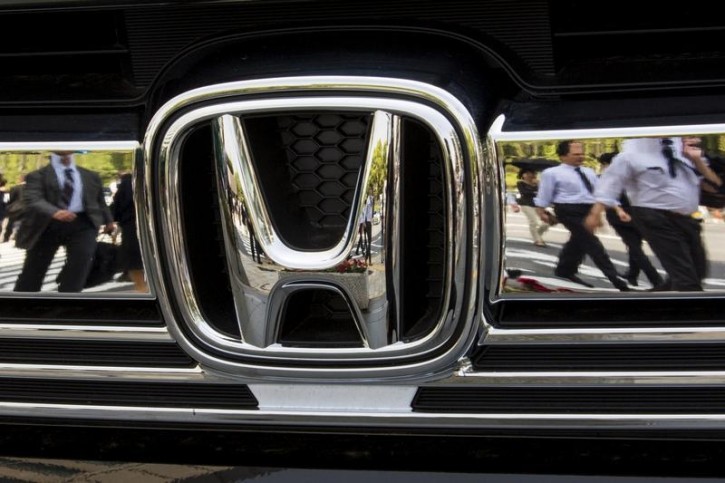FILE - People are reflected in the chrome front grill of a Honda car outside the Japanese car maker's headquarters in Tokyo April 28, 2015.  Reuters