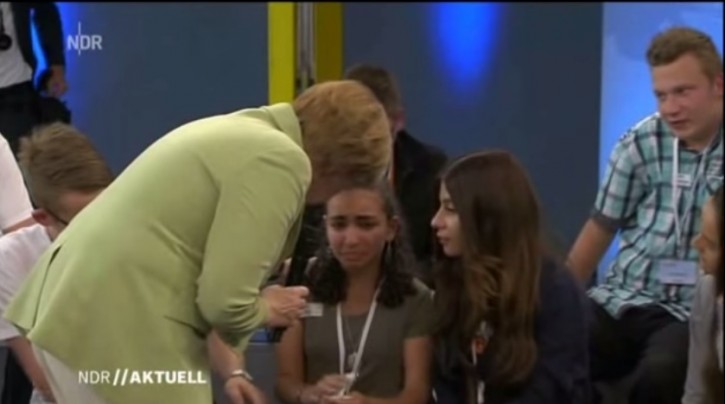 Merkel attempts to comfort a crying girl during their encounter. Photo: Norddeutsche Rundfunk/Screenshot