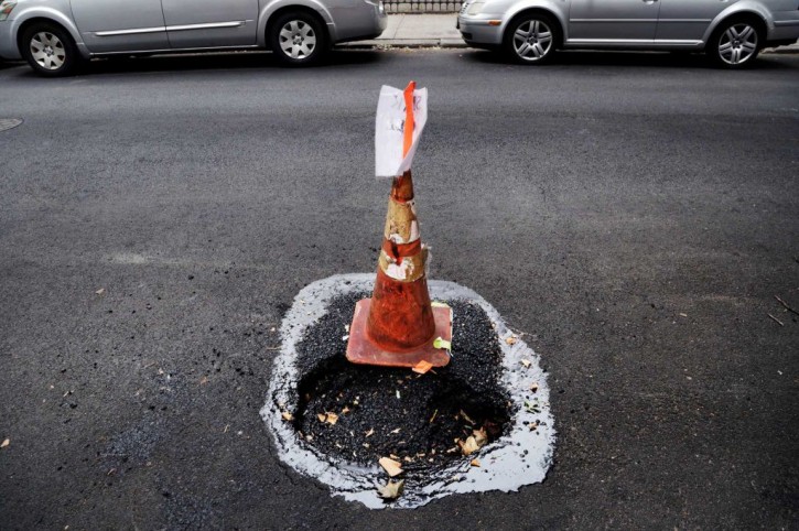 An orange construction cone stands next to a pothole in the Park Slope neighborhood of the Brooklyn borough of New York, Thursday, July 30, 2015.  AP