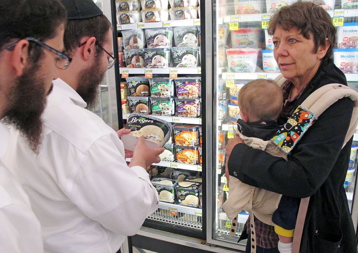 In this July 27, 2015 photo, orthodox Jewish rabbi Dovid Lepkivker, center, examines a container of Breyer's ice cream, which happens to be kosher, as fellow rabbi Eli Chaikin, left, and Mary Semple look on in Helena, Mont. Lepkivker and Chaikin are on a mission to reach as many Montana Jews as they can in a month to teach them how to keep kosher. (AP Photo/Matt Volz)