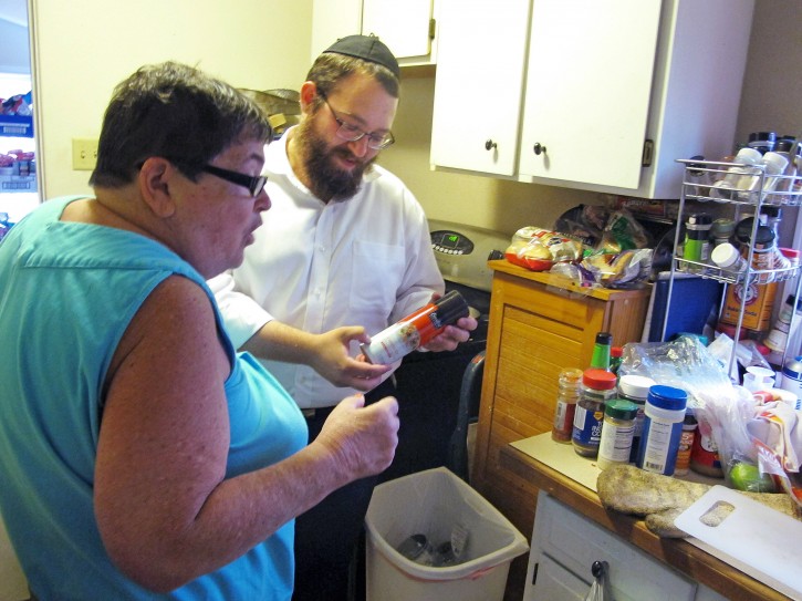 In this July 27, 2015 photo, orthodox Jewish rabbi Dovid Lepkivker, right, points out a kosher certification label on a container as Beth Pagel gives him a tour of her kitchen, in Helena, Mont. Lepkivker and fellow rabbi Eli Chaikin are on a mission to reach as many Montana Jews as they can in a month to teach them how to keep kosher. (AP Photo/Matt Volz)
