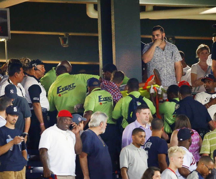 Emergency medical personnel carry an injured fan from the stands at Turner Field during a baseball game between Atlanta Braves and New York Yankees Saturday, Aug. 29, 2015, in Atlanta. A fan has been given emergency medical treatment and been taken to a hospital after falling from the upper deck into the lower-level stands at Turner Field during a game between the New York Yankees and Atlanta Braves. (AP Photo/John Bazemore)