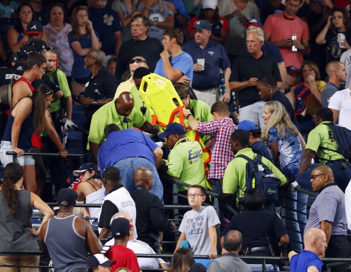 Emergency medical personnel  attend to an injured fan in the stands at Turner Field during a baseball game between Atlanta Braves and New York Yankees Saturday, Aug. 29, 2015, in Atlanta. A fan fell from the upper deck into the lower-level stands at Turner Field on Saturday night, and was given emergency medical treatment before being taken to a hospital during the game between the Yankees and Atlanta Braves. (AP Photo/John Bazemore)