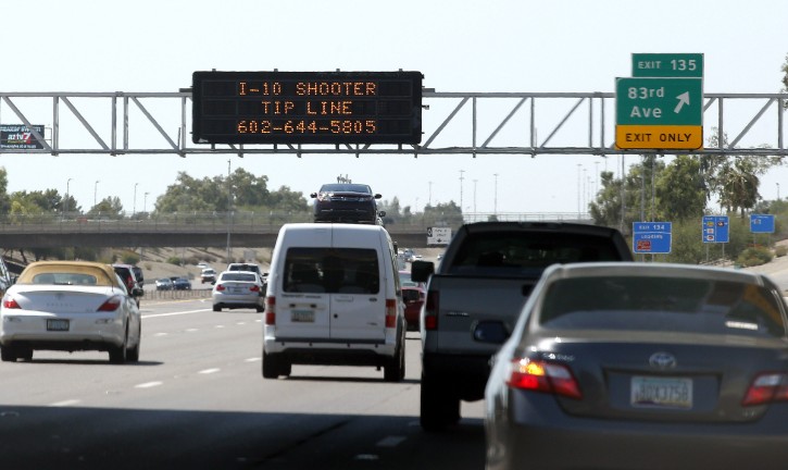 A sign still displays a shooter tip line above Interstate 10, Friday, Sept. 11, 2015, in Phoenix. Authorities have a person of interest in custody in a string of freeway shootings over the past two weeks and the man's white Chevrolet Tahoe, raising hopes of a resolution to the rash of freeway shootings rattling the metro area. (AP Photo/Ross D. Franklin)