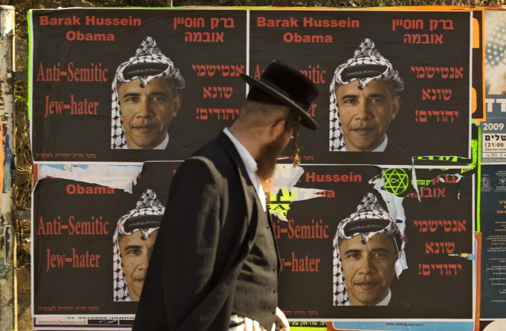 FILE - In this Sunday, June 14, 2009 file photo, an ultra Orthodox Jewish man walks past posters hung by an extremist right wing group, depicting U.S. President Barack Obama, wearing a traditional Arab headdress, in Jerusalem. Seeking to sell his nuclear deal with Iran to a skeptical Israeli public, Obama has repeatedly declared his deep affection for the Jewish state. But the feelings do not appear to be mutual. (AP Photo/Sebastian Scheiner, File)