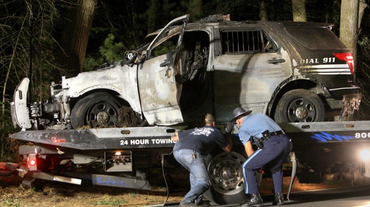 FILE - A police officer assists as a cruiser that was shot at is removed from Forest Road, Wednesday, Sept. 2, 2015 in Millis, Mass.  (John Blanding/The Boston Globe via AP, Pool)