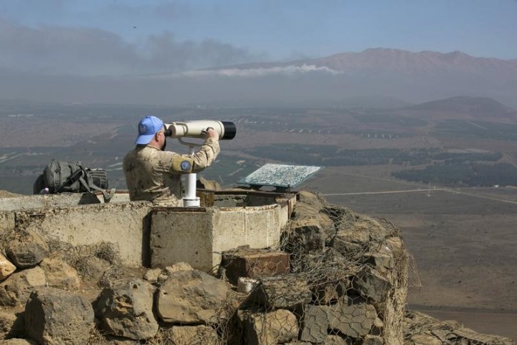 FILE - A Canadian member of the United Nations Disengagement Observer Force (UNDOF) looks through binoculars at Mount Bental, an observation post in the Israeli occupied Golan Heights near the ceasefire line between Israel and Syria August 21, 2015. Reuters