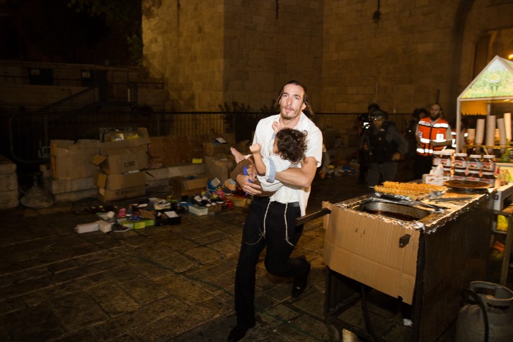 A Jewish man carries a baby injured in a stabbing attack in the Old City of Jerusalem on October 3, 2015. A Jewish family was stabbed while walking near the Lion's Gate in the Old City. The father died of his wounds. The terrorist was shot down by police. Photo by Yonatan Sindel/Flash90