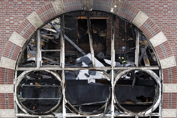 An investigator looks through the rubble in the burned shell of the Poile Zedek Synagogue on  Saturday, Oct. 24, 2015, in New Brunswick, N.J.  Authorities say a fire that destroyed the historic New Jersey synagogue on Friday appears to be accidental. (AP Photo/Mel Evans)