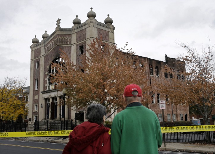 A couple stops to look at the burned shell of the Poile Zedek Synagogue from a fire Friday, on Saturday, Oct. 24, 2015, in New Brunswick, N.J.  Authorities say a fire that destroyed the historic New Jersey synagogue appears to be accidental. (AP Photo/Mel Evans)