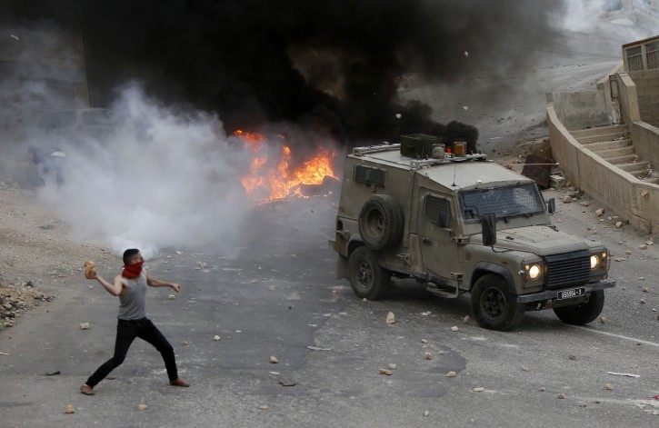 Palestinian youths throw rocks at Israeli military vehicle during a raid in the West Bank city of Nablus, Tuesday, Oct. 6, 2015. Israeli Prime Minister Benjamin Netanyahu warned Monday that he will use a "strong hand" to quell violent Palestinian protests and deadly attacks, signaling that the current round of violence is bound to escalate at a time when a political solution to the conflict is increasingly distant. (AP Photo/Majdi Mohammed)