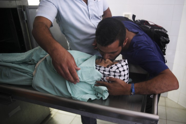 A man kisses 13-year-old Palestinian Abdel Rahman Shadi in a morgue in the town of Bethlehem, West Bank, Monday, Oct. 5, 2015. Shadi died after being hit by a live bullet to the chest during clashes between Palestinians and Israeli security forces, a doctor at a hospital near the clashes said. (AP Photo/Mahmoud Illean)