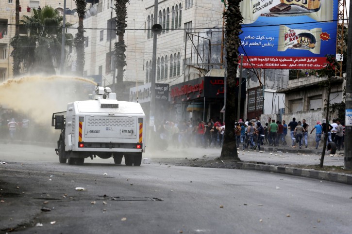 An Israeli Police car sprays water on Palestinian protesters during clashes with Israeli security forces in the West Bank city of Hebron, 23 October 2015.  EPA