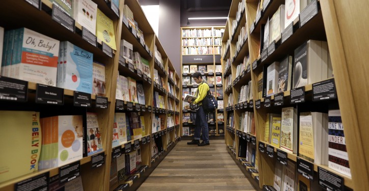 A customer shops at the opening day for Amazon Books, the first brick-and-mortar retail store for online retail giant Amazon, Tuesday, Nov. 3, 2015, in Seattle. The company says the Seattle store, coming two decades after it began selling books over the Internet, will be a physical extension of its website, combining the benefits of online and traditional book shopping. Prices at the store will be the same as books sold online. (AP Photo/Elaine Thompson)