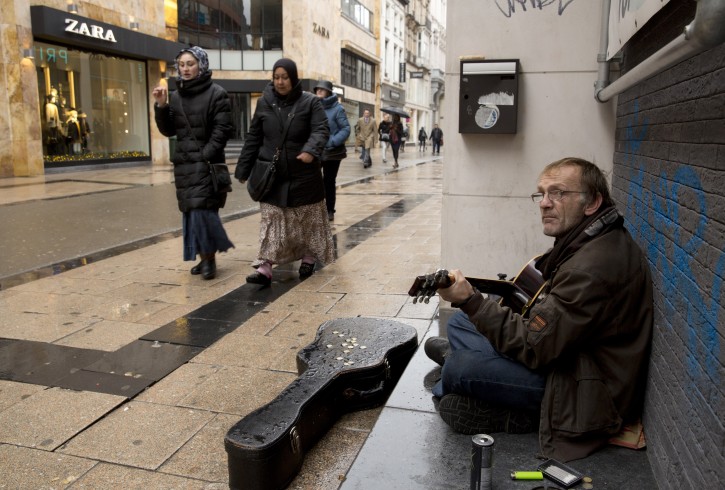 Two women walk by a street musician on an otherwise busy shopping street in Brussels on Saturday, Nov. 21, 2015. Belgium raised its security level to its highest degree on Saturday as the manhunt continues for extremist Salah Abdeslam who took part in the Paris attacks. The security levels shut down all metro lines and shuttered many shops as well as canceling sports matches. (AP Photo/Virginia Mayo)