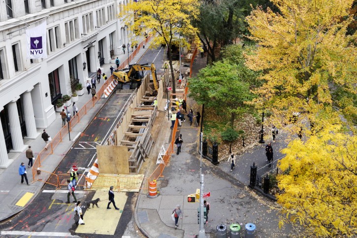 A plywood wall surrounds the opening to an underground construction area, Thursday, Nov. 5, 2015 in the Greenwich Village neighborhood of New York. Two burial vaults discovered beneath a street in the heart of New York University's campus by workers replacing a water main were likely part of a Presbyterian church cemetery, an archaeologist said Thursday. (AP Photo/Mark Lennihan)