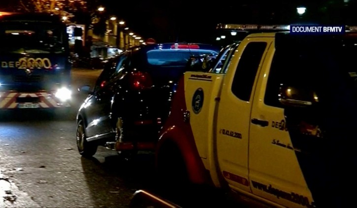 This image taken from BFMTV, shows a car being towed away accompanied by security vehicles, in Montreuil, a suburb of Paris, overnight Saturday/Sunday Nov. 14/15, 2015. A Seat car with suspected links to the Paris attacks has been found by police in Montreuil. An official could not immediately confirm if this was the same black Seat linked to the gun attacks on the Le Carillon bar and the Le Petit Cambodge restaurant in Rue Alibert in the city's 10th district. (BFMTV via AP)