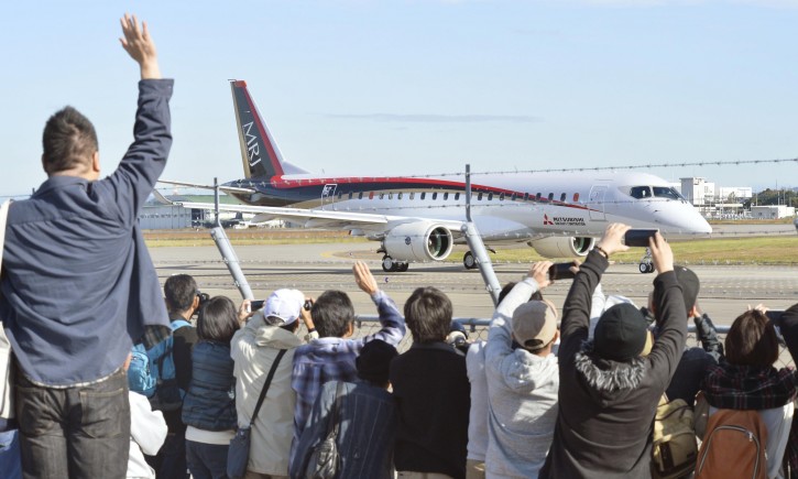 Spectators wave and take photos of Japan's first domestically produced passenger jet, the Mitsubishi Regional Jet (MRJ), taking off from Nagoya Airport in Toyoyama, central Japan, for its first flight Wednesday morning, Nov. 11, 2015. Mitsubishi, a maker of the Zero fighter, took a step toward reclaiming Japan's one-time status as an aviation power Wednesday with the maiden flight of its regional jet. (Yoshiaki Sakamoto/Kyodo News via AP) 