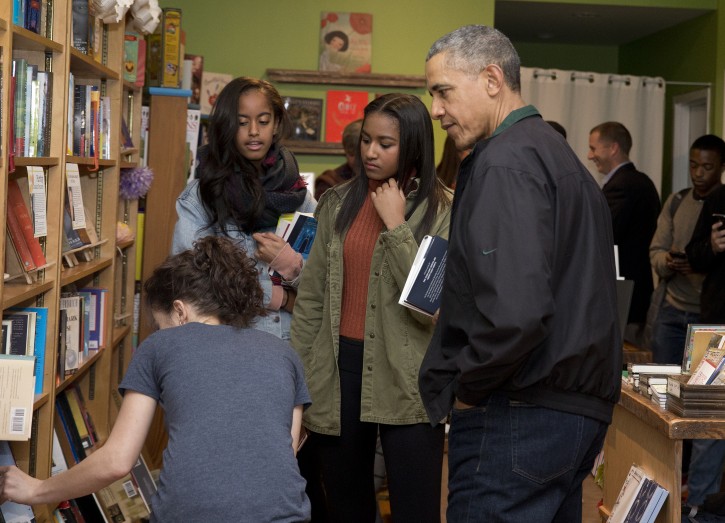 President Barack Obama, right, joined by his daughters Malia, second from left, and Sasha, second from right, talks with manager Anna Thorn, left, as they shop at Upshur Street Books on Small Business Saturday in Washington, Saturday, Nov. 28, 2015. (AP Photo/Carolyn Kaster)