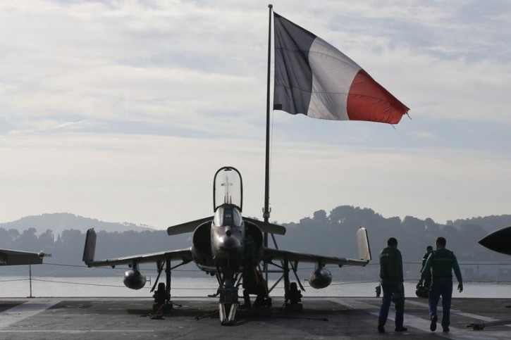 Flight deck crew work around a Super Etendard fighter jet as a French flag flies aboard the French nuclear-powered aircraft carrier Charles de Gaulle before its departure from the naval base of Toulon, France, November 18, 2015. Reuters