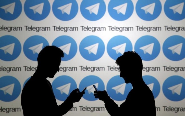 Two men pose with smartphones in front of a screen showing the Telegram logos in this picture illustration taken in Zenica, Bosnia and Herzegovina November 18, 2015. REUTERS