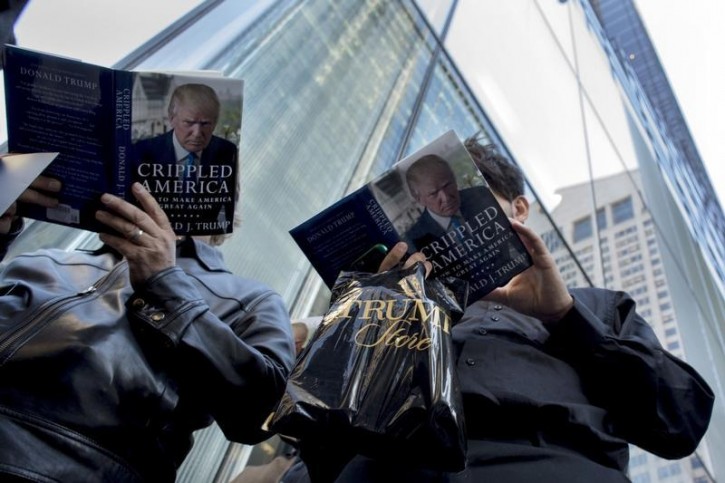 People read as they wait in line for Republican presidential candidate Donald Trump to sign copies of his new book "Crippled America" in the Manhattan borough of New York, November 3, 2015. REUTERS/Brendan McDermid -