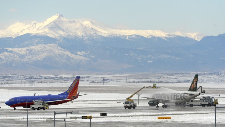A plane, right, is de-iced at Denver International Airport in Denver, after a powerful wintery storm dumped heavy snow on parts of Colorado, Tuesday, Nov. 17, 2015.  A snow-covered Longs Peak is in the background. (Cyrus McCrimmon/The Denver Post via AP) 