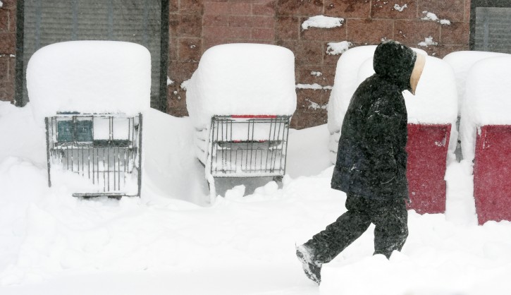 A man walks past nearly buried shopping carts at the Kings Soopers in Monument, Colo., on Tuesday, Nov. 17, 2015. A powerful wintery storm blasted parts of Colorado with heavy snow on Tuesday while bringing the threat of tornadoes to millions in Texas, where a handful of damaging twisters had plowed through the Panhandle the day before. (Jerilee Bennett/The Gazette via AP)