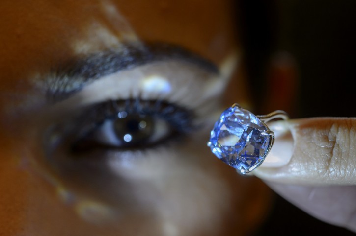 FILE - In this Nov. 4, 2015 file photo a Sotheby's employee displays the rare Blue Moon Diamond during a preview at  Sotheby's, in Geneva, Switzerland. The 12.03 carat blue diamond is the largest cushion shaped fancy vivid blue diamond  ever appear at auction. It is estimated to sell between 35 and 55 million US dollars. The auction will take place in Geneva, on Nov. 11, 2015. (Martial Trezzini/Keystone via AP, file)