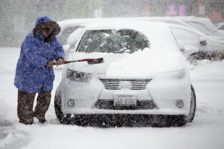 A woman cleans snow from her car on Saturday, Nov. 21, 2015, in Northbrook, Ill. The first significant snowstorm of the season blanketed some parts of the Midwest with more than a foot of snow and more was on the way Saturday, creating hazardous travel conditions and flight delays. (AP Photo/Nam Y. Huh)