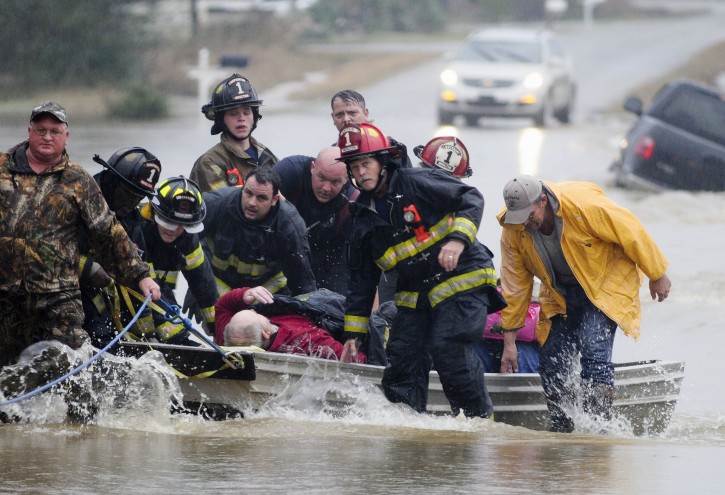 Emergency officials transport James Simmons by boat because water over Byler Road prevented them from reaching him in Moulton, Ala., Friday, Dec. 25, 2015. AP