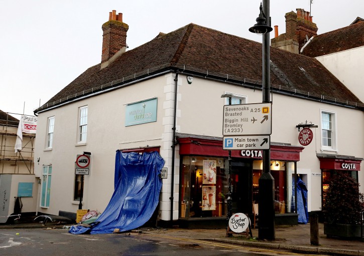 The scene in Westerham, England, with a blue tarp covering the impact site where a car ploughed into a Costa coffee shop,  Thursday Dec. 24, 2015.  The car smashed into the coffee shop, leaving one woman dead and five other people injured. (Steve Parsons  / PA via AP) 