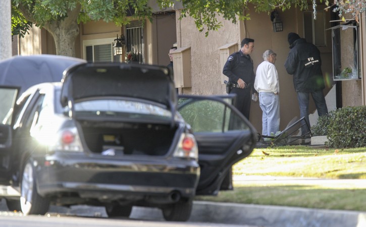 FBI agents interview a man, center, outside a home in connection to the shootings in San Bernardino, Thursday, Dec. 3, 2015, in Redlands, Calif. A heavily armed man and woman opened fire Wednesday on a holiday banquet for his co-workers, killing multiple people and seriously wounding others in a precision assault, authorities said. Hours later, they died in a shootout with police. (AP Photo/Ringo H.W. Chiu)