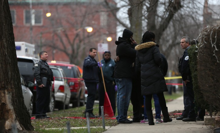 Chicago police officers talk with relatives of one of the two people killed by a police officer, as they investigate a shooting in the entry of their apartment in Chicago on Saturday, Dec. 26, 2015. A Chicago police officer shot and killed two people while responding to a domestic disturbance call in the neighborhood on the city's West Side, police said. (Abel Uribe/Chicago Tribune via AP)