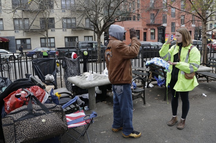 An unidentified homeless man, center, and Jennifer Sherry communicate using sign language at the man's encampment in Tompkins Square Park, Monday, Dec. 21, 2015 in New York. Sherry works for Goddard Riverside Community Center which is contracted by the city of New York to do outreach work with the homeless. (AP Photo/Mark Lennihan)
