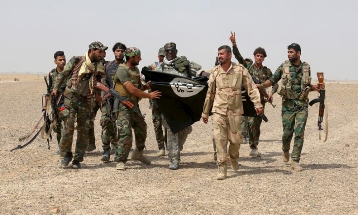 FILE - Iraq's Shi'ite paramilitaries and members of Iraqi security forces hold an Islamist State flag which they pulled down in Nibai, in Anbar province May 26, 2015.  Reuters