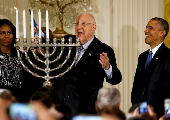 Israeli President Reuven Rivlin (C) lights a menorah as he joins U.S. President Barack Obama (R) for a Hanukkah reception at the White House in Washington December 9, 2015. Also pictured is U.S. first lady Michelle Obama (L).  REUTERS/Jonathan Ernst   